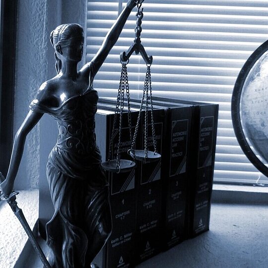 A desk in dim lightning, a statue of Justicia on the left, a globe on the right.