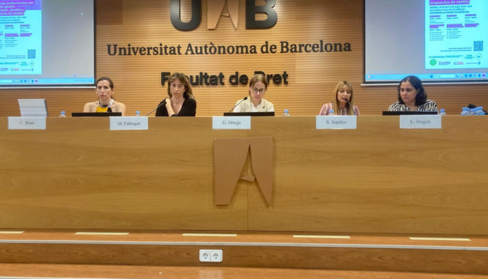 Photo of a panel of five women with the logo of the Universidad Autónoma de Barcelona in the background