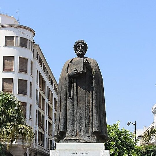 A statue of Ibn Khaldoun in the middle of a square.