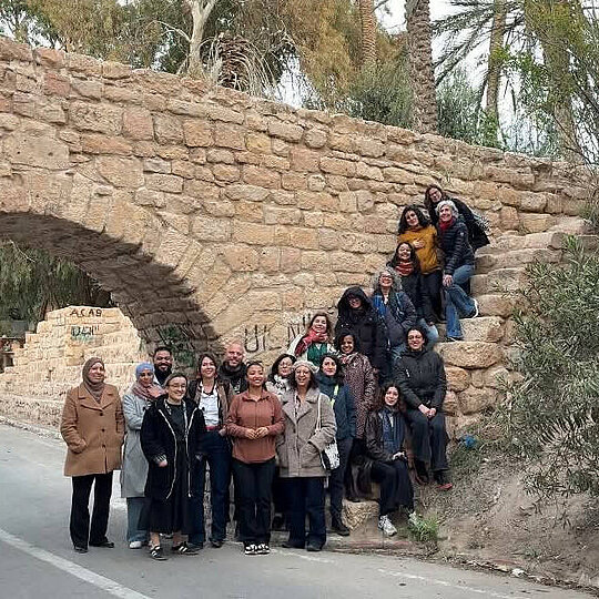 A group of people in front of a bridge built out of stone.