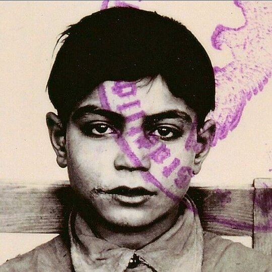 Old photograph of a boy, above it a rubber stamp.