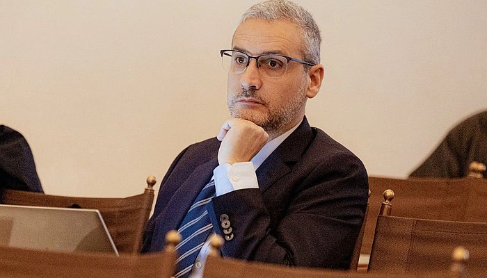 A man sitting in a row of chairs, listening
